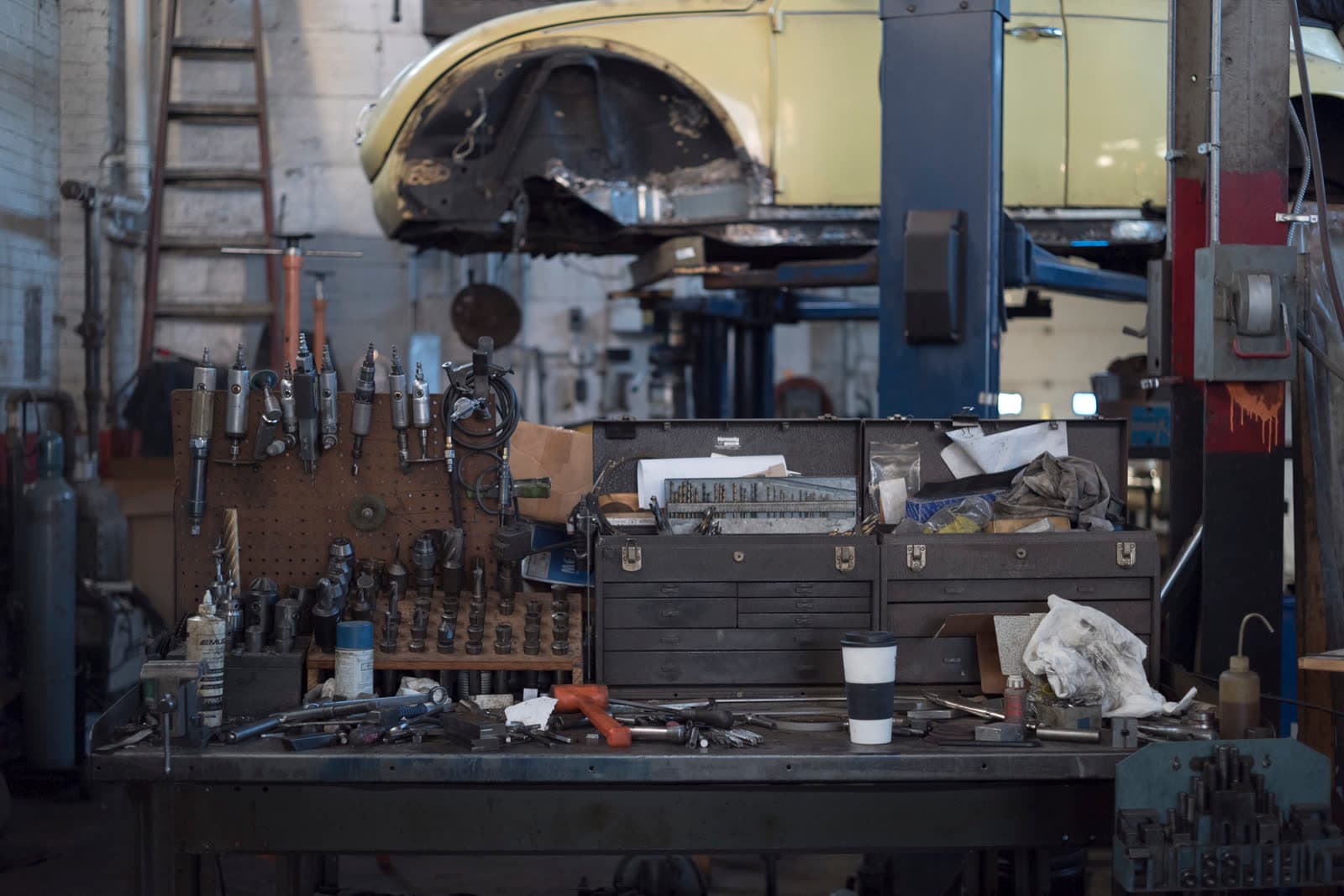 A car on a lift above a working bench of tools and a toolbox