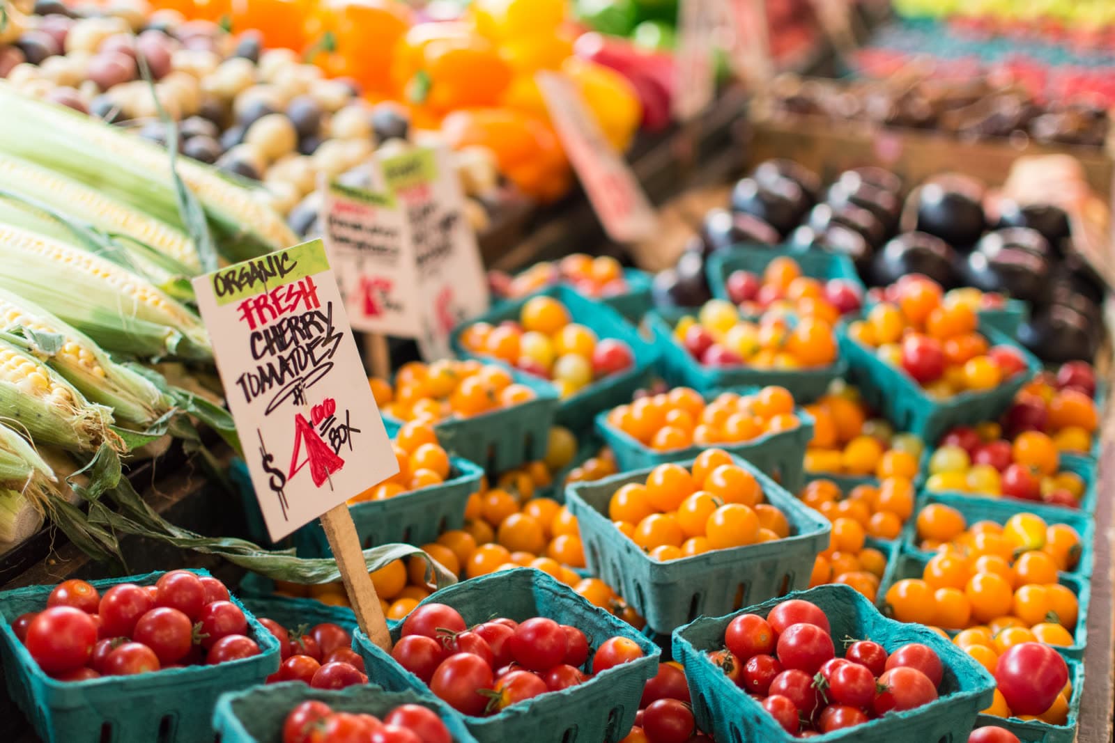 Punnets of tomatoes and corn on a market stall